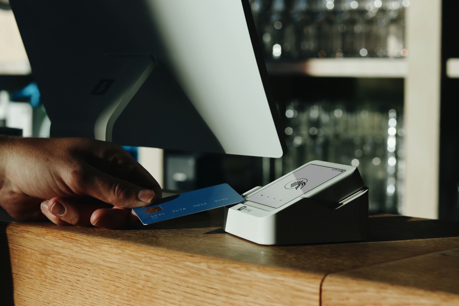A customer tapping a card to pay on a countertop payment terminal